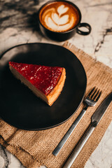 Strawberry cheesecake served on a black plate with coffee latte