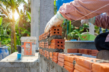 masonry worker make concrete wall by cement block and plaster at construction site