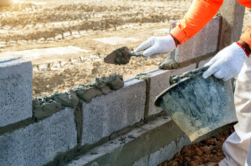 masonry worker make concrete wall by cement block and plaster at construction site