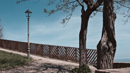 A fenced park with trees and a lamppost overlooking the Mediterranean Sea (Marche, Italy, Europe)