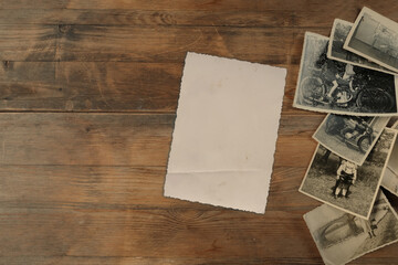stack of old vintage monochrome photographs on photographic paper on natural wood background,...