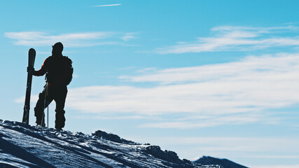 Silhouette of a Hiker wearing a backpack on a mountain peak during the daytime. High quality photo
