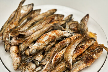 Fried golden small smelt delicious fish on a white plate