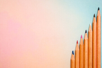 Regenbogenfarbener Hintergrund mit einer Anordnung von Buntstiften. Mit großem Textfeld