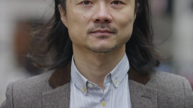 Portrait of handsome Asian professional looking to camera and smiling, in slow motion
