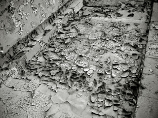 Black and white image of an old damaged wall with cracks on the paint
