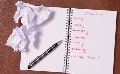 ToDo Liste für eine Woche. Aufgeschlagenes Notizbuch mit schwarzem  Einband auf braunem...