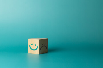 Wooden cube with smiley face and bad face on green background. Service rating, satisfaction concept