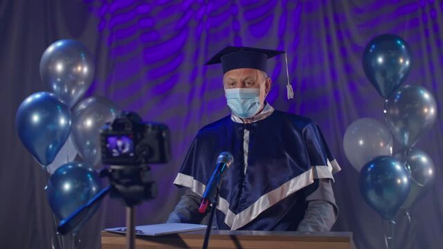 male lecturer wearing medical mask observes precautions congratulate graduates on graduation online via video link during pandemic and quarantine