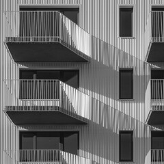 Detail of an apartment building with balconies on a sunny day. Distinctive lines, light and shadow.