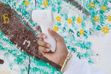 Doctor holding a medical infrared forehead thermometer to check body temperature for virus symptoms