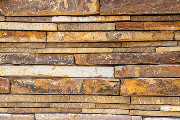 Dry stacked stone wall made of large slabs of colorful sandstone background