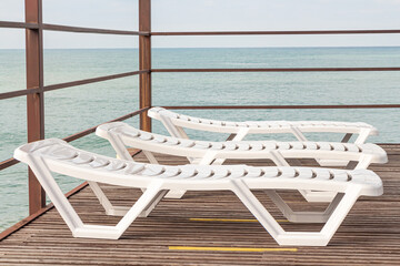 Group of Beautiful white plastic sunbeds is on the beach by sea
