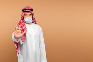 Fototapeta na wymiar An Arab man in national dress shows a stop gesture with his hand. Dishdasha, kandora, thobe, coronovirus, Protection against contagious disease. Copy space.