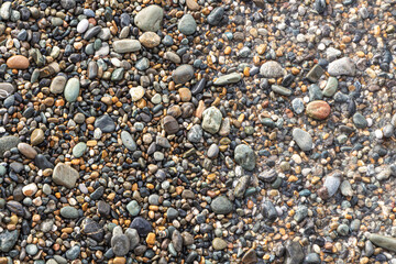 Beautiful texture of colorful smooth stones is on the beach by sea