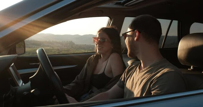 Side View of Young Couple on Road Trip, Man and Woman Talk While Sitting in the Car, Travel Concept