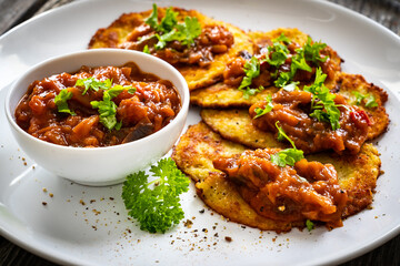 Potato pancakes with vegetable stew on wooden table
