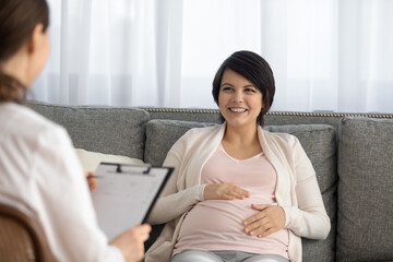 Happy young Caucasian pregnant woman talk consult with gynecologist in private clinic or hospital....
