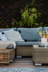 Wicker coffee table and sofa with pillows on the patio of beautiful garden