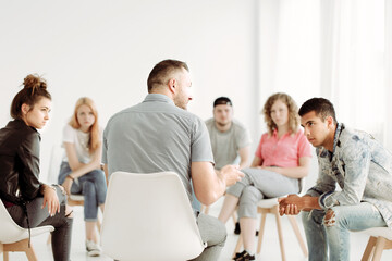 Professional Therapist with group of rebellious teenagers during psychotherapy session