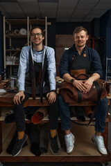 leather craftsmen working making measupenets in patterns at table in workshop studio