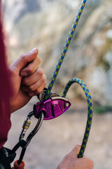 Close up photo of a belay device used by climbers. Climbing gear in action. Belay with a rope and a...
