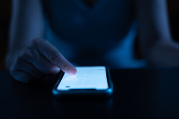 Woman working on cellphone at night, Finger touching on smartphone with dark background