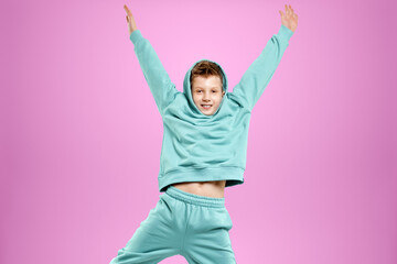 Portrait, cute stylish boy in a blue suit on a pink background. Studio portrait of a child, modern design, trendy background, turquoise. Copy space.