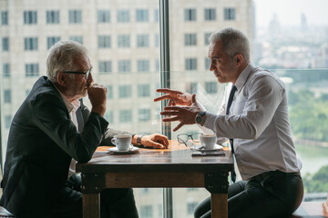 Two businessmen discussing in the corporate high-rise lounge, professional business people meeting 