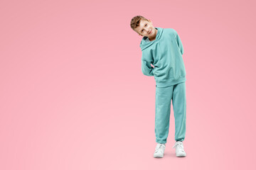 Fototapeta premium Portrait, cute stylish boy in a blue suit on a pink background. Studio portrait of a child, modern design, trendy background, turquoise. Copy space.