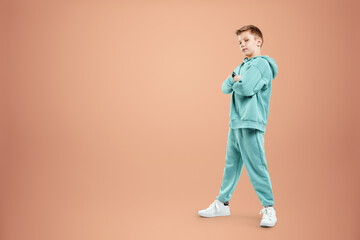 Fototapeta na wymiar Portrait, cute stylish boy in a blue suit on a beige background. Studio portrait of a child, modern design, trendy background, turquoise. Copy space.