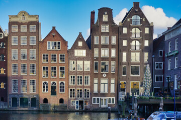 Fototapeta na wymiar Amsterdam houses on Damrak a partially filled in canal dancing houses with dutch architecture by the canal Amsterdam Holland Netherlands