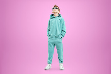 Portrait, cute stylish boy in a blue suit on a pink background. Studio portrait of a child, modern design, trendy background, turquoise. Copy space.