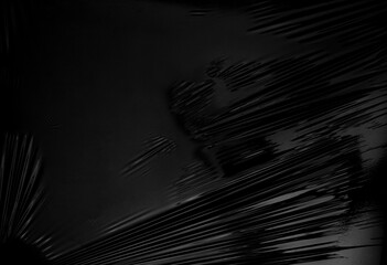 a transparent stretch plastic wrap on black background. realistic plastic wrap texture for overlay and effect. wrinkled plastic pattern for creative and decorative design.
