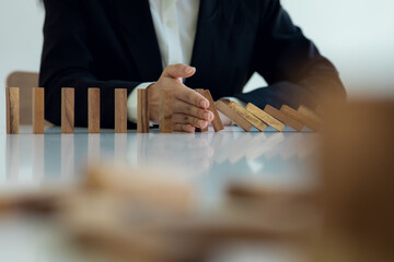 Close up finger businesswoman stopping wooden block from falling in the line of domino with Investment Insurance Alternative and preven,Business risk contro concept.