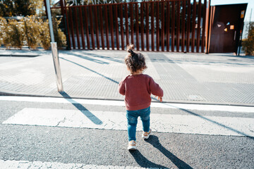 Back View Of Long Haired Adorable Toddler On Blue Jean Trousers and Purple Jacket
