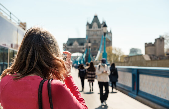 Back of a mature woman taking a picture of the Tower bridge.