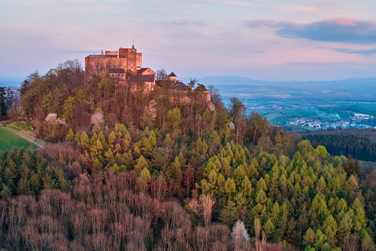 Buchlov Castle. Aerial view on monumental castle, standing on a wooded hill, lit by reddish light of setting sun. Spring time, tourist hotspot. Moravia castle, Czech republic.