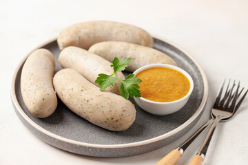 Munich white sausage with sweet mustard on paper plate.