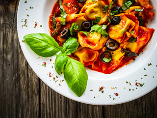 Tortelloni stuffed with prosciutto ham and vegetables on wooden table
