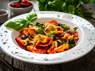 Tortelloni stuffed with prosciutto ham and vegetables on wooden table
