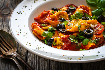 Tortelloni stuffed with prosciutto ham and vegetables on wooden table
