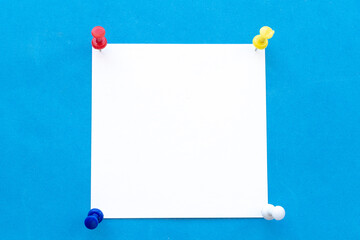 White note paper attached by four pins on a blue background