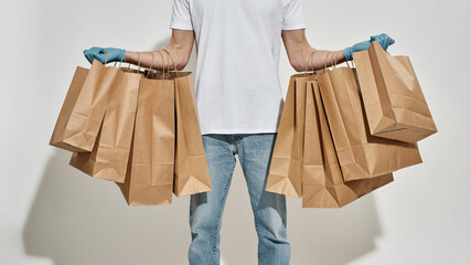 Cropped photo of delivery guy hands hung all over with paper bags
