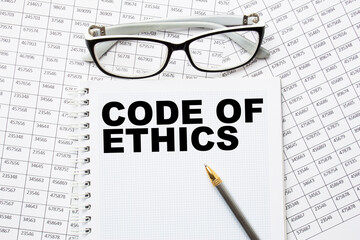 Notepad with text CODE OF ETHICS on the office desk with stationery. A blank notepad for entering a copy or text. business