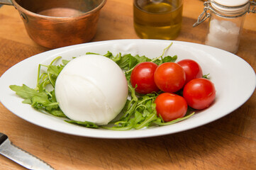 real Italy buffalo mozzarella in a dish with cherry tomatoes and rocket from Campania and Puglia region in Italy