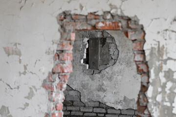 An end-to-end hole in a brick wall inside an old abandoned and ruined industrial building covered with paint in a collapsed building with through holes. High quality photo bad interior.