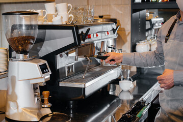 Close-up of a masked barista preparing a delicious coffee at the bar in a cafe. The work of restaurants and cafes during the pandemic.