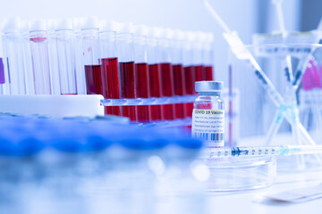 Glass bottle vial and syringe with Covid-19 Coronavirus vaccine in a research medical facility lab. Ampoules with cure on the medical worker laboratory table. Sars-cov-2 pandemic concept.