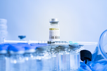 Vaccine vials and syringes containing COVID 19 cure. Ready to administer the shot. Medical research against Coronavirus. Drugs, medications and ppe on the table of medical worker.